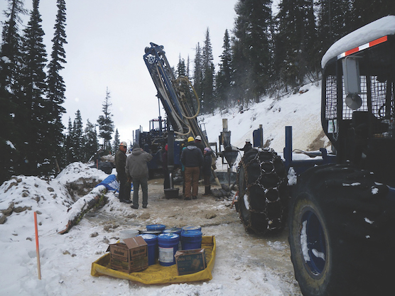 heavy machinery clearing forest with men in coats as they operate a drilling machine at the Kilgore Project area site
